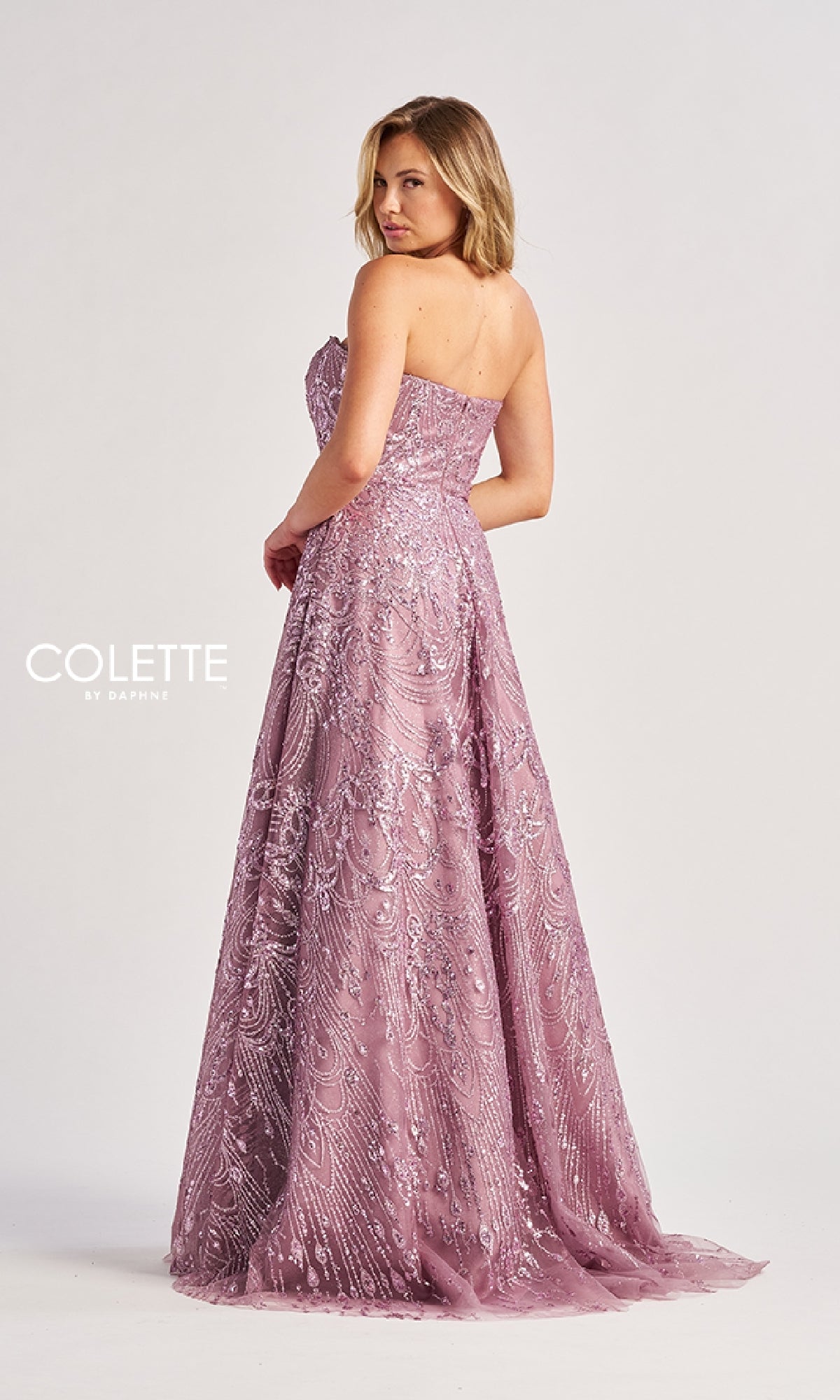 A woman wears the Colette CL8625, a long prom dress in lavender with strapless design and intricate sequin and bead detailing, posing against a plain background.